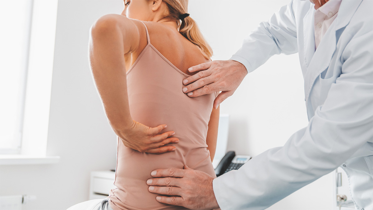 Eine Patientin zeigt dem Arzt ihre Problem-Schmerzzonen am Rücken. 