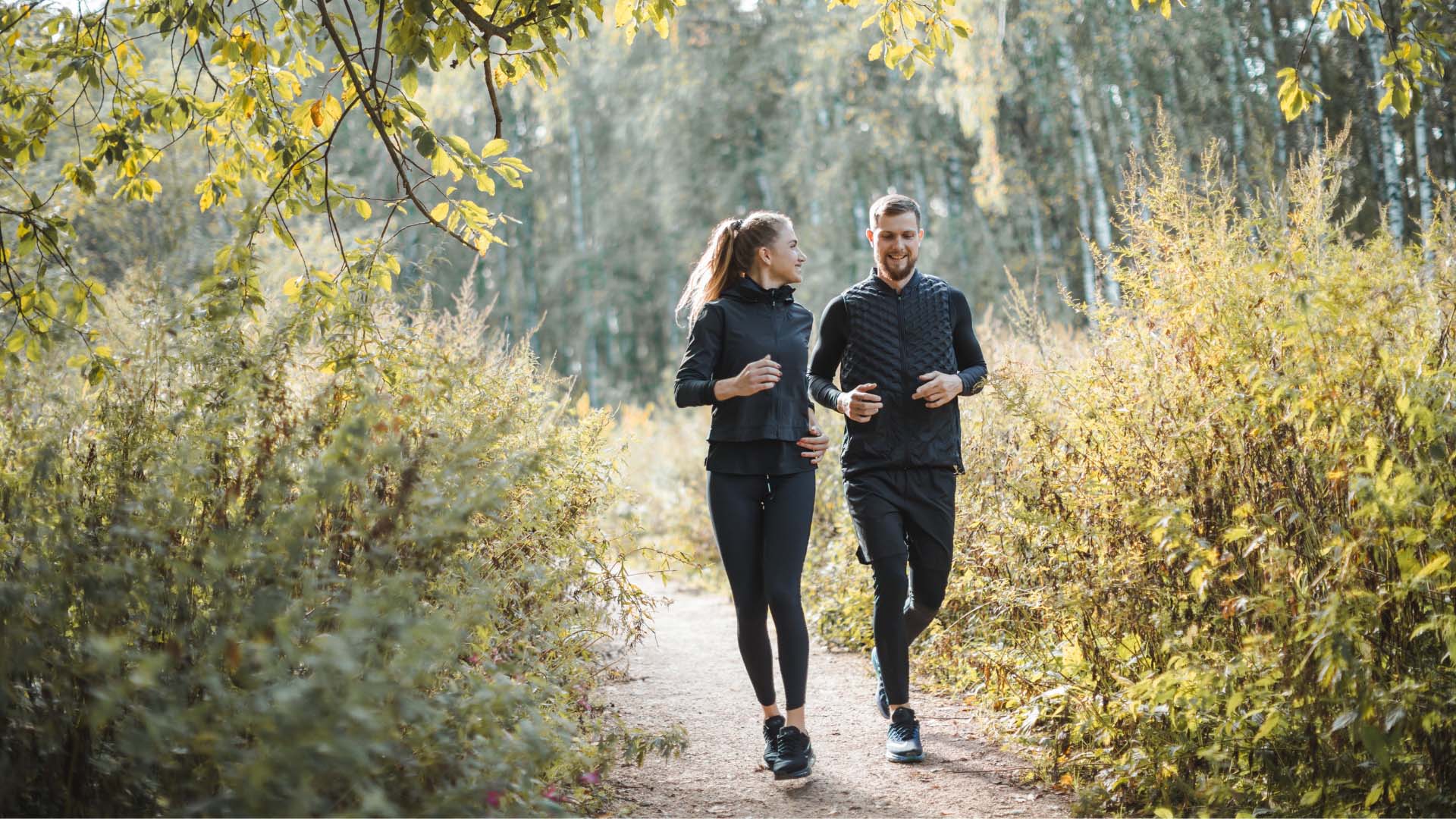 Eine Frau und ein Mann beim Joggen durch den Wald.
