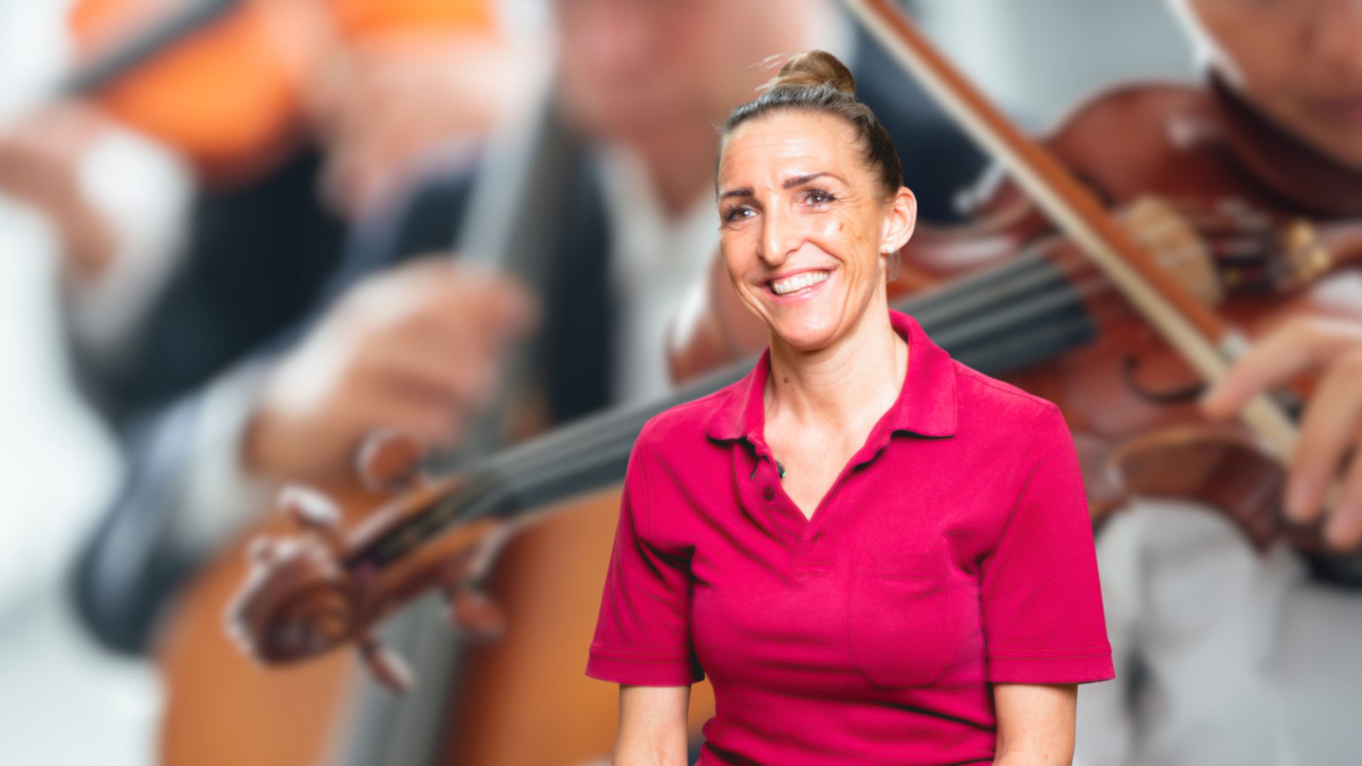 Frau Silja Pfeiffer, Stv. Leitung der Therapie der DR. ERLER REHA und Diplom-Musiklehrerin im Fach Violine, mit Violinen Spielern im Hintergrund. 
