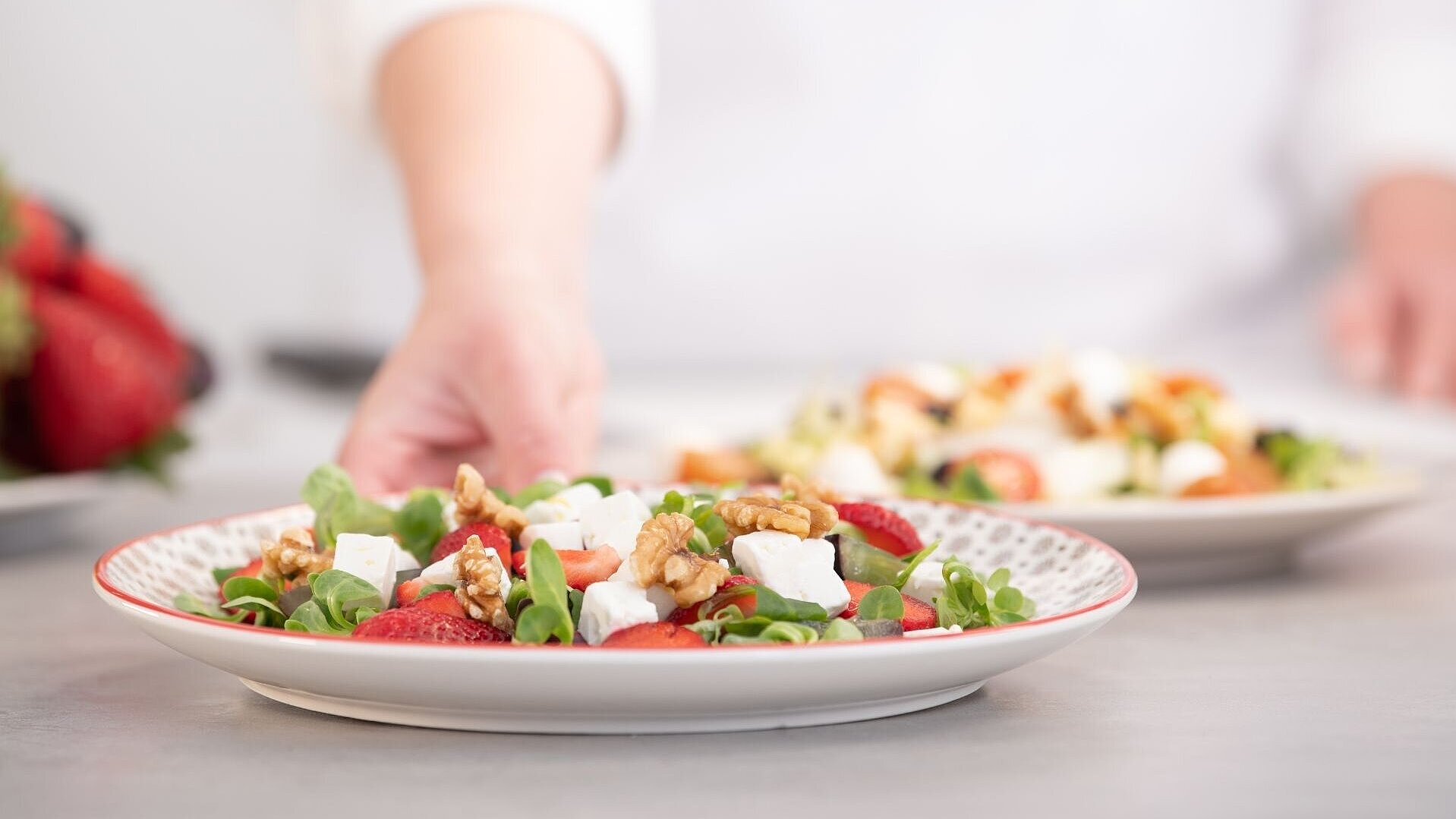 Ein angerichteter Salatteller wird von einem Koch gehalten.